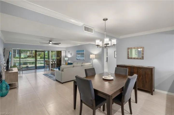 Dining space with crown molding, visible vents, baseboards, and ceiling fan with notable chandelier