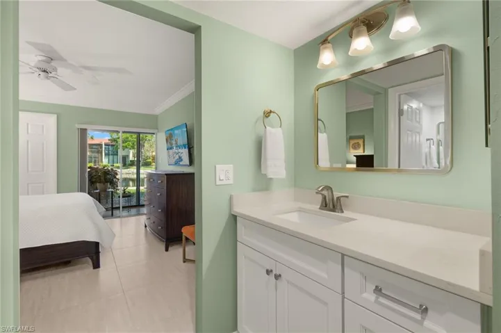 Ensuite bathroom featuring vanity, ceiling fan, tile patterned floors, ensuite bath, and crown molding