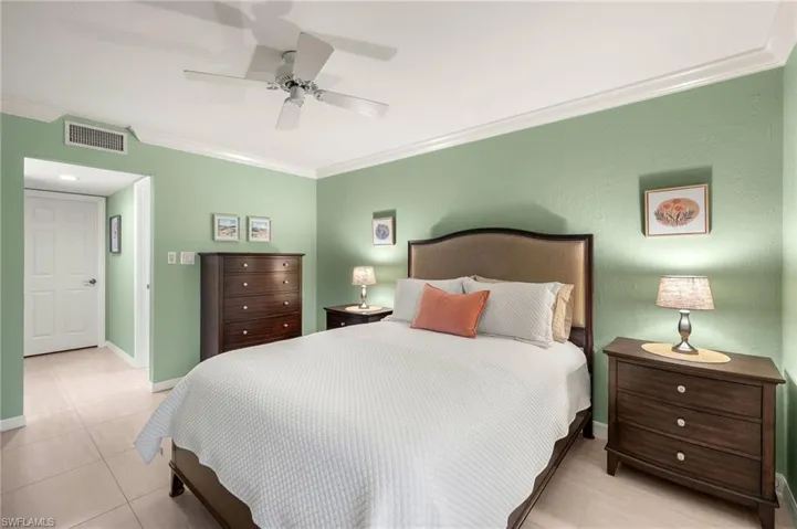 Bedroom featuring visible vents, baseboards, light tile patterned flooring, ornamental molding, and a ceiling fan