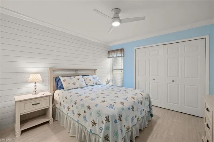 Bedroom featuring ceiling fan, wooden walls, a closet, and crown molding
