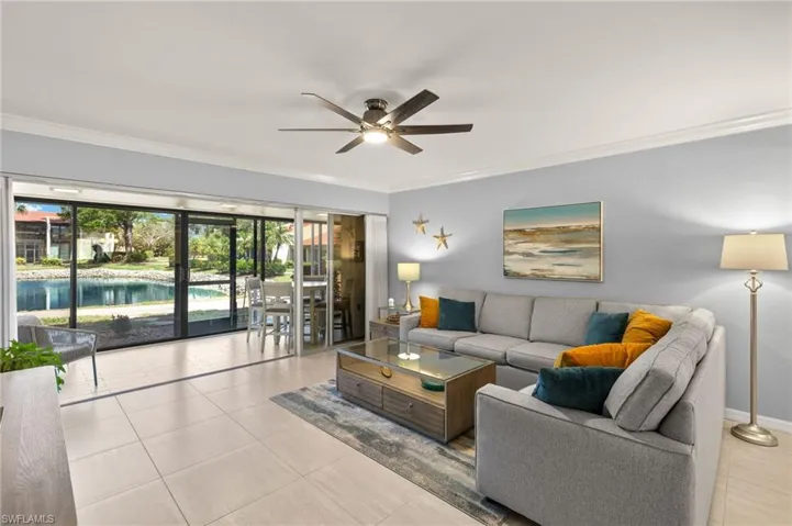 Tiled living area featuring ornamental molding and a ceiling fan