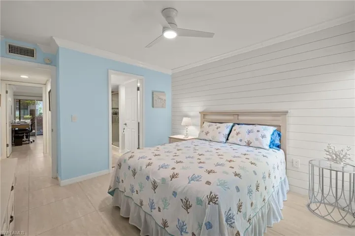 Bedroom featuring ornamental molding, light tile patterned floors, visible vents, and wood walls