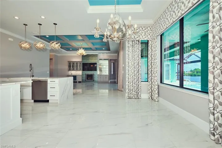 Kitchen with crown molding, a chandelier, white cabinets, open floor plan, and coffered ceiling