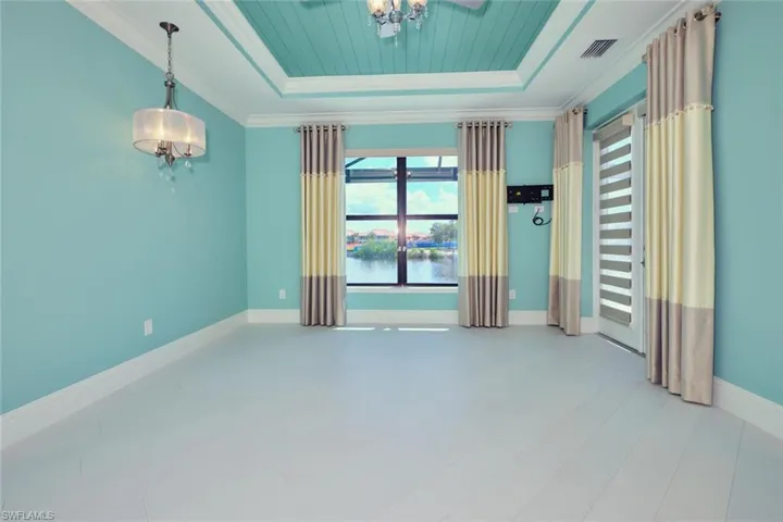 Unfurnished room featuring a raised ceiling, crown molding, a water view, and a chandelier
