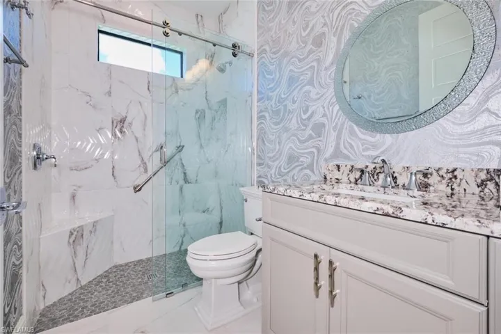 Full bath featuring a marble finish shower and vanity