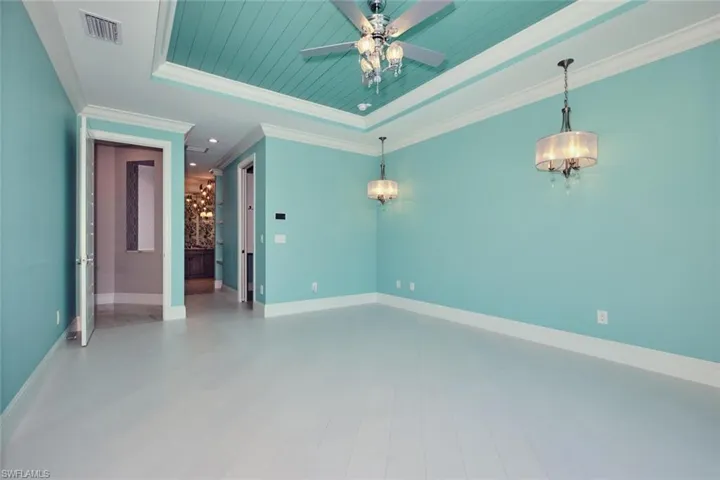 Unfurnished room featuring a raised ceiling, ceiling fan, wood finished floors, and ornamental molding