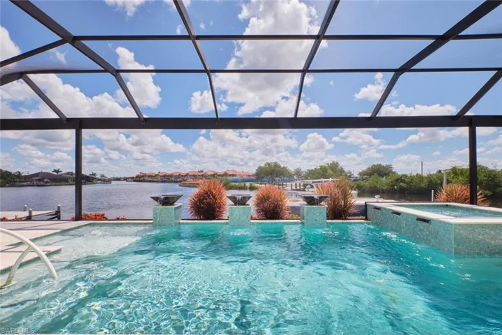 View of pool with a water view, a pool with connected hot tub, and glass enclosure