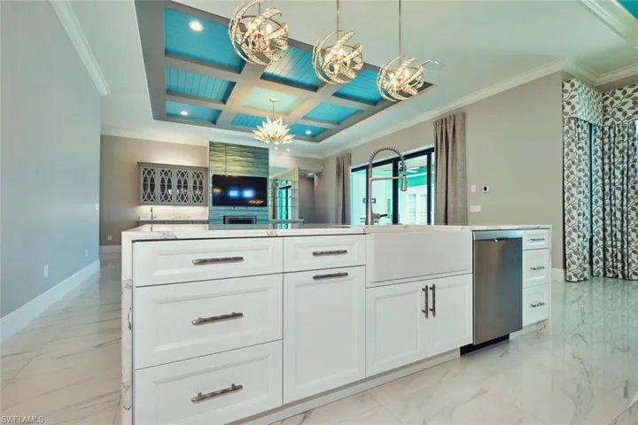 Kitchen featuring stainless steel dishwasher, ornamental molding, a chandelier, coffered ceiling, and white cabinets