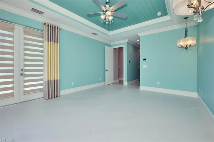 Unfurnished room featuring a chandelier, a tray ceiling, ornamental molding, and a ceiling fan