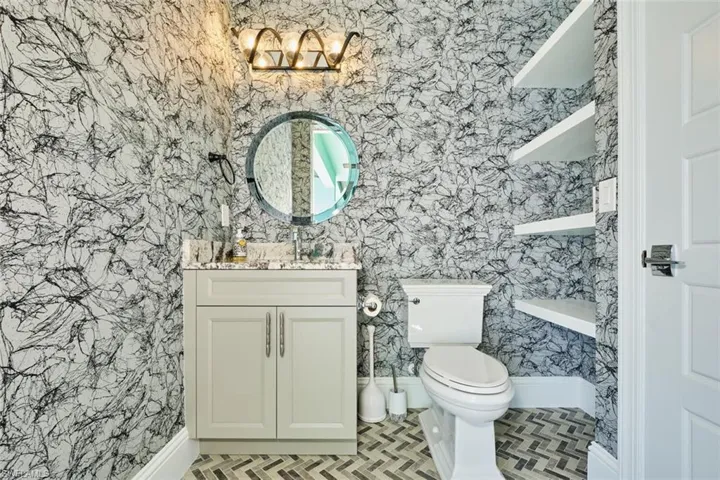 Bathroom featuring wallpapered walls, vanity, tile patterned floors, and a chandelier
