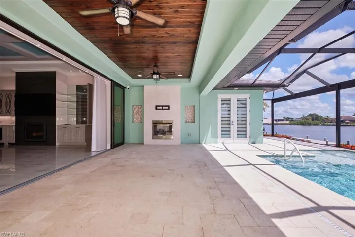 View of patio featuring french doors, a ceiling fan, a water view, an outdoor pool, and a lanai