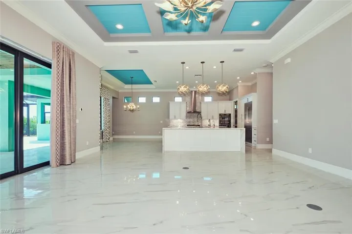Unfurnished living room with a chandelier, crown molding, light marble finish flooring, and recessed lighting