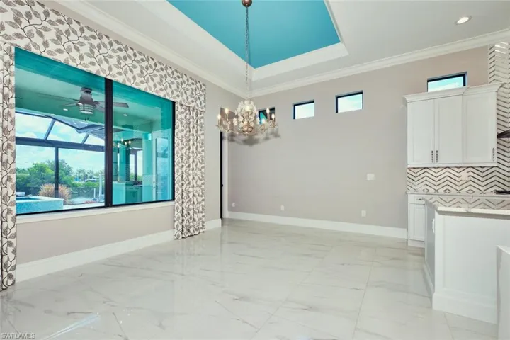 Empty room with light marble finish flooring, crown molding, a chandelier, ceiling fan, and recessed lighting