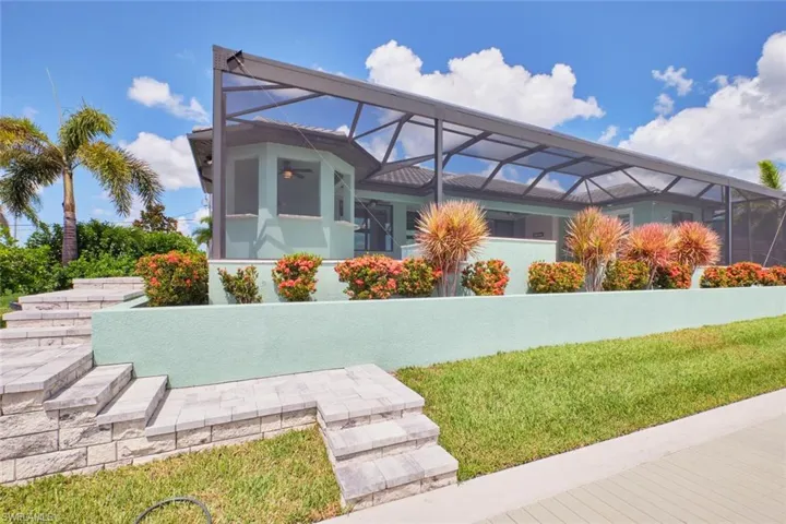 Back of property featuring glass enclosure and a lawn