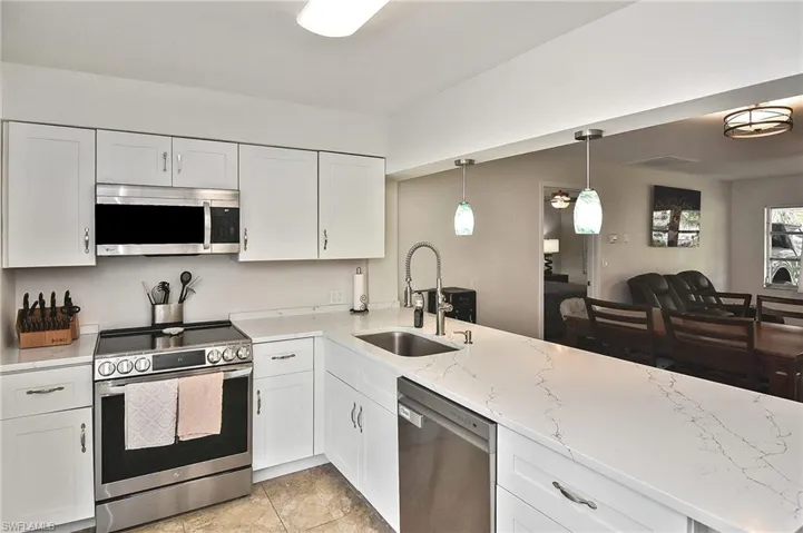 Kitchen featuring light stone countertops, a sink, white cabinets, and stainless steel appliances