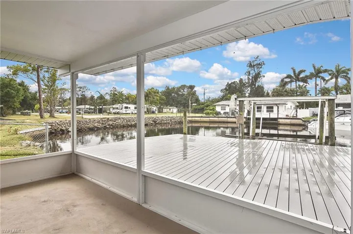 Wooden deck with boat lift, a dock, and a water view