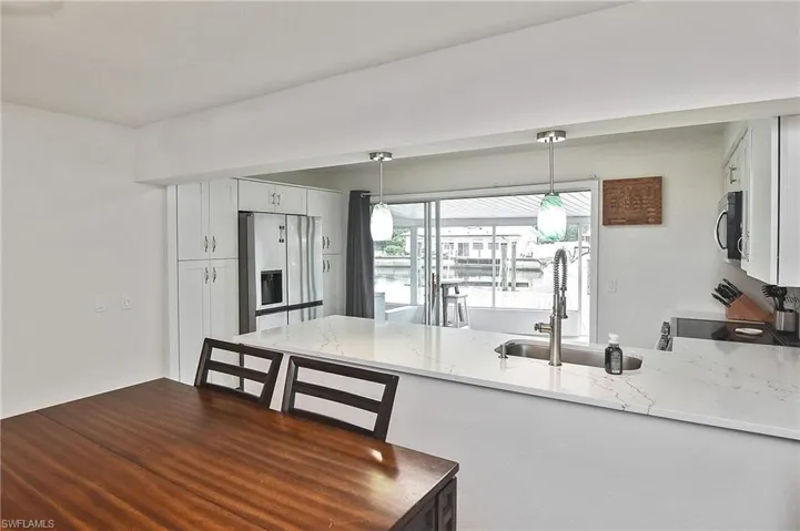 Kitchen with a sink, a peninsula, light stone counters, and stainless steel appliances