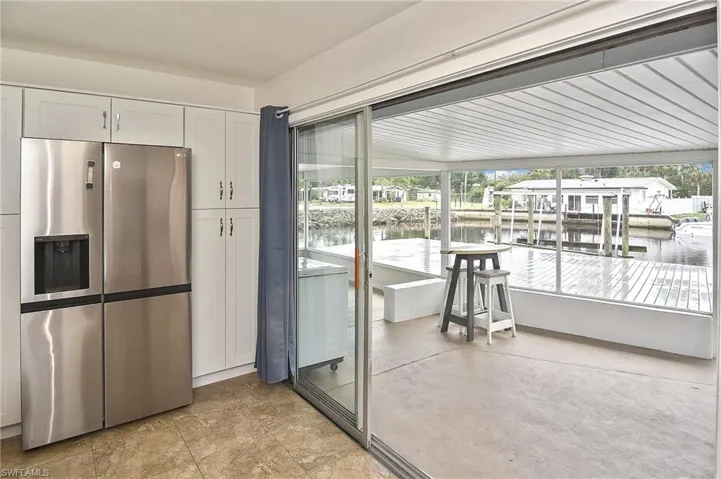 Kitchen featuring stainless steel fridge with ice dispenser, white cabinets, and a water view