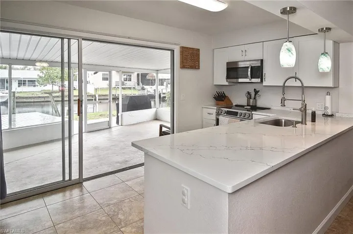 Kitchen featuring a wealth of natural light, light stone countertops, a sink, and appliances with stainless steel finishes