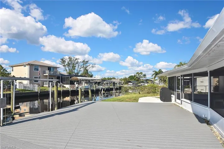 Deck with a sunroom, a boat dock, and a water view