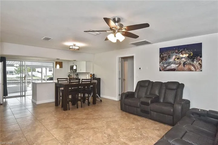 Living area with light tile patterned flooring, baseboards, a ceiling fan, and visible vents