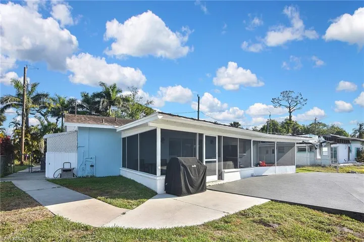 Back of property with a sunroom, a yard, and stucco siding