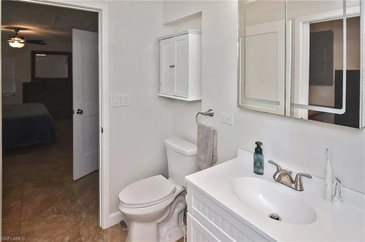 Bathroom featuring toilet, ceiling fan, and vanity