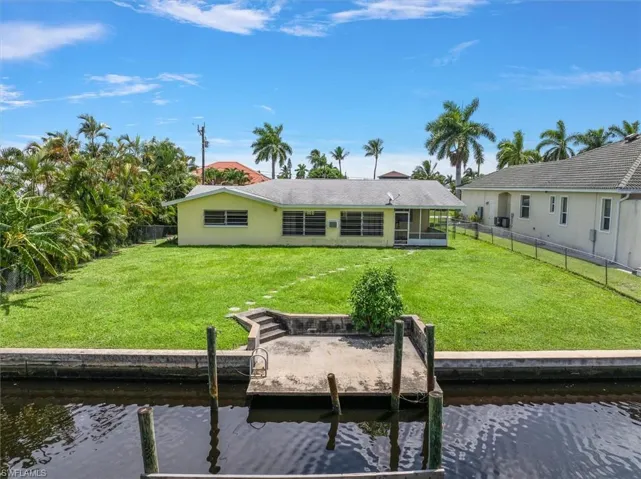 Back of house with a lawn and a water view