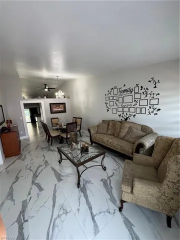 Tiled living room featuring ceiling fan with notable chandelier