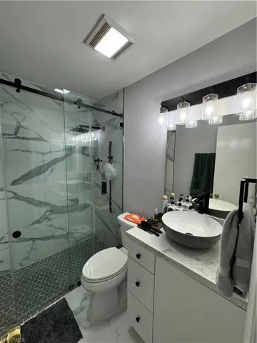 Bathroom with tile patterned floors, vanity, an enclosed shower, and toilet