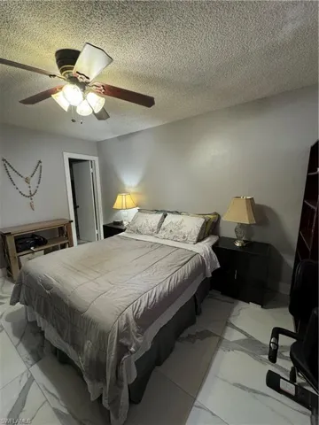 Tiled bedroom with a textured ceiling and ceiling fan
