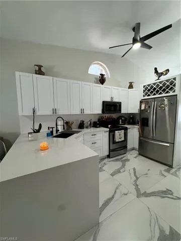Kitchen with range, fridge, white cabinets, and kitchen peninsula