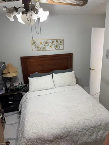 Bedroom with tile patterned floors, a textured ceiling, and ceiling fan