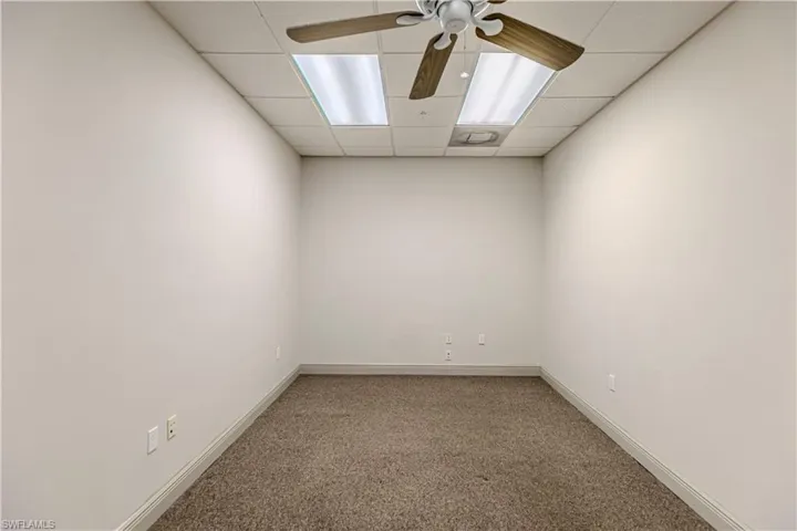 Carpeted spare room featuring ceiling fan and a drop ceiling