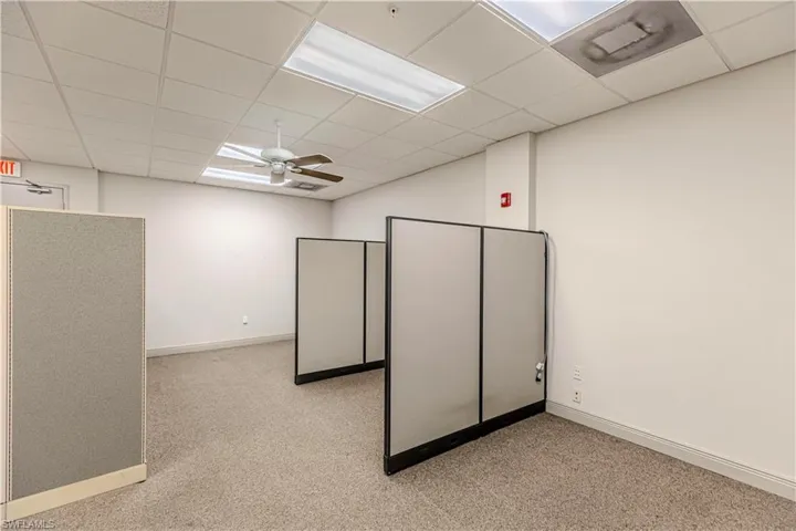 Carpeted empty room with a drop ceiling and ceiling fan