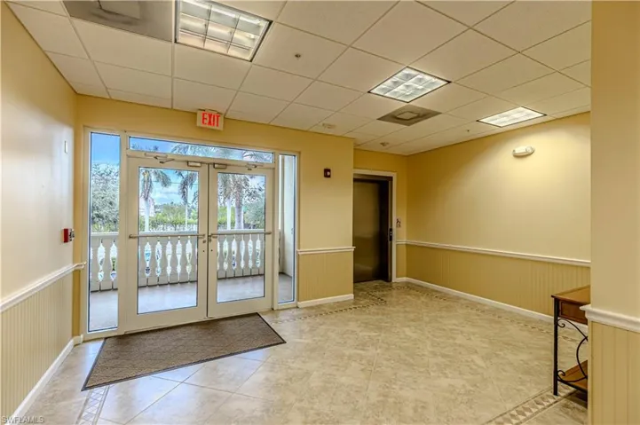 Doorway featuring a paneled ceiling, light tile patterned floors, and french doors