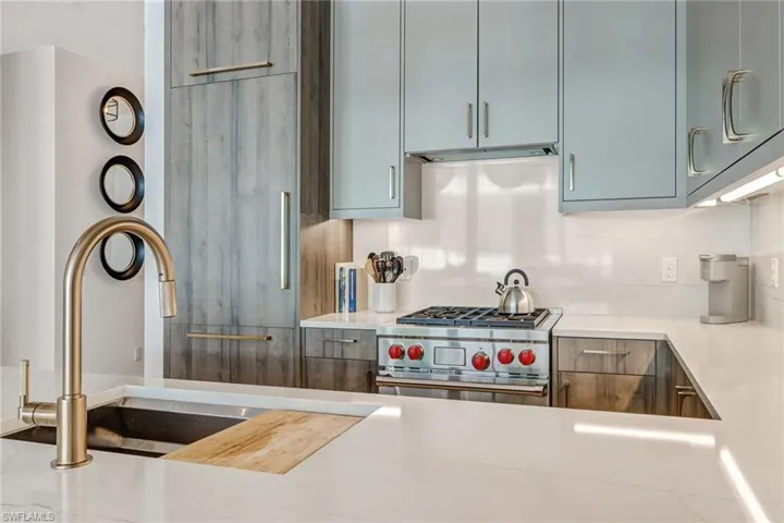 Kitchen with designer stove, modern cabinets, light stone countertops, and decorative backsplash
