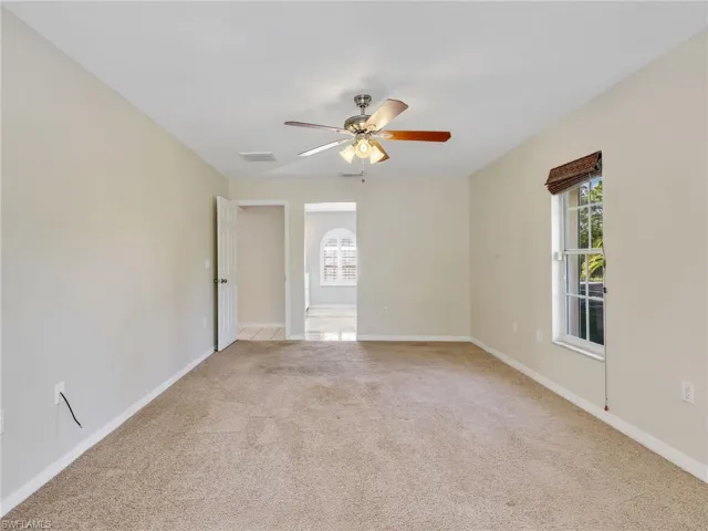 Primary bedroom featuring light colored carpet, healthy amount of natural light, and a ceiling fan