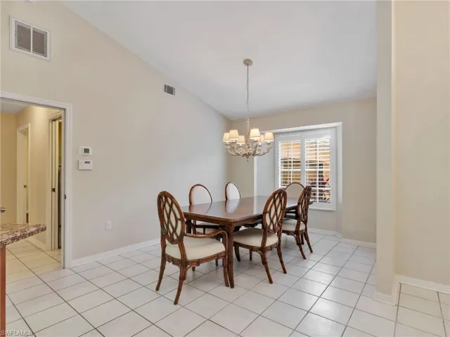 Dining room featuring vaulted ceiling, light tile patterned floors, and a chandelier