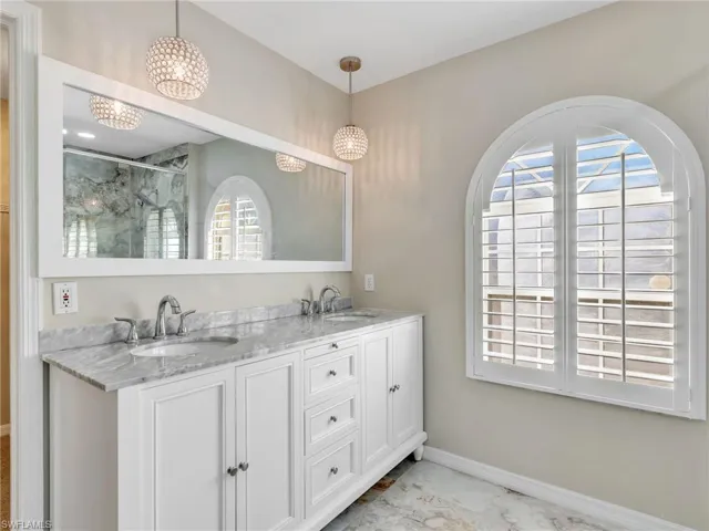 Bathroom with double vanity, a stall shower, and a chandelier