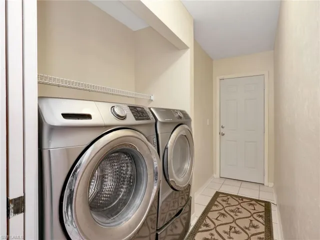 Laundry area featuring light tile patterned floors and washing machine and dryer