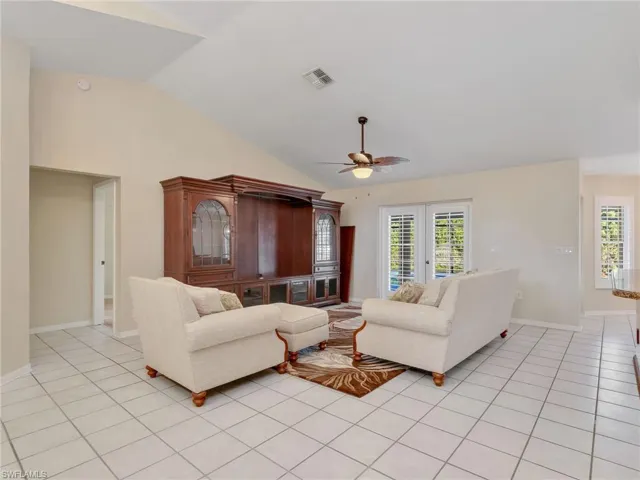 Living area featuring healthy amount of natural light, lofted ceiling, light tile patterned floors, and a ceiling fan