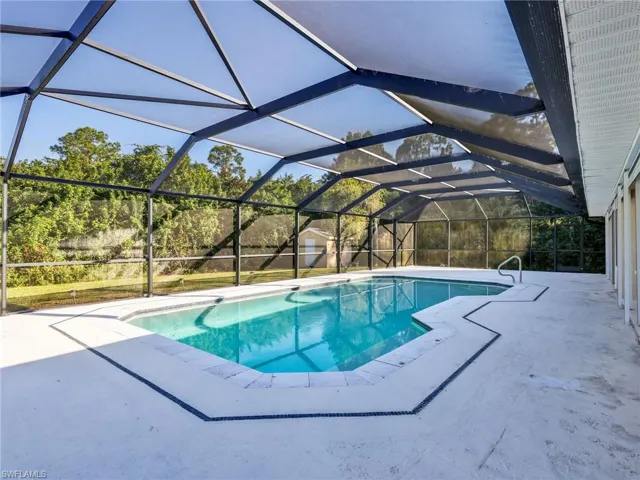Swimming pool featuring a sunroom, a lanai, a patio area, and a storage unit