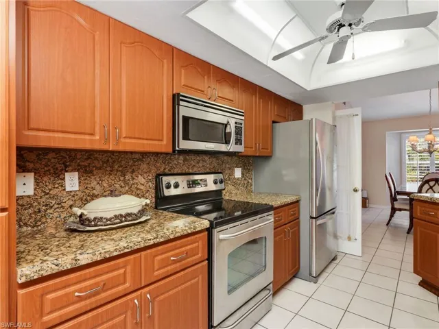 Kitchen with stainless steel appliances, light stone counters, and brown cabinets