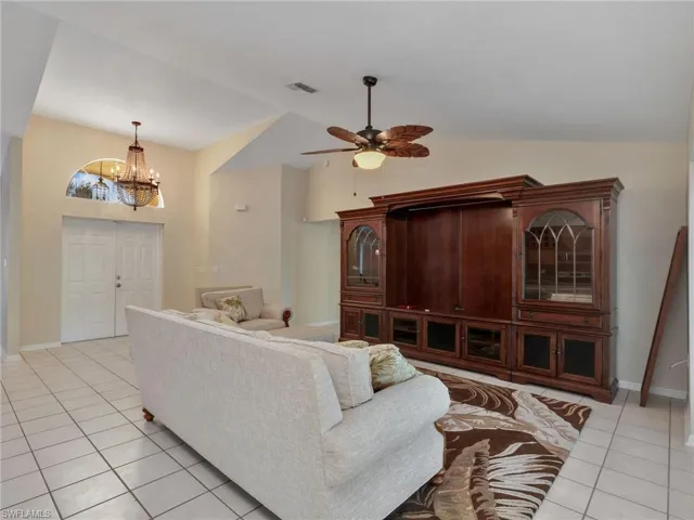 Living area featuring light tile patterned floors, a chandelier, a ceiling fan, and high vaulted ceiling