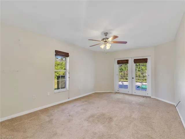 Primary bedroom with light colored carpet, french doors, and ceiling fan