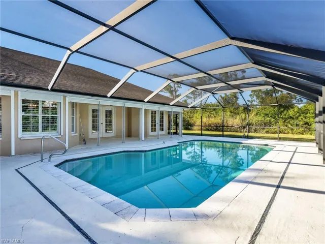 Swimming pool featuring a patio area, a sunroom, a lanai, and french doors