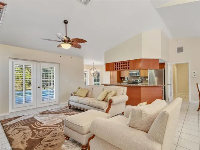 Living room with light tile patterned floors, french doors, a ceiling fan, and vaulted ceiling