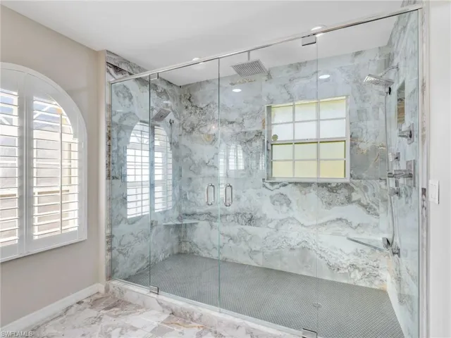 Bathroom featuring marble finish floors, plenty of natural light, and a marble finish shower
