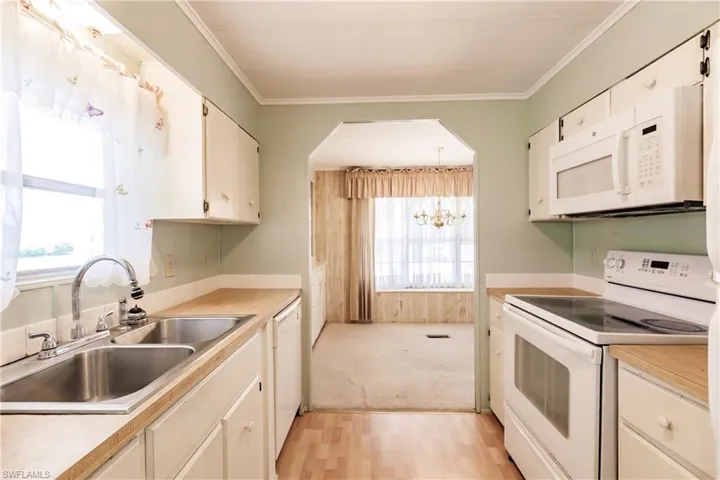 Kitchen featuring white appliances, plenty of natural light, sink, and light colored carpet